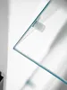 A close-up view of a glass shelf attached to a wall with a clear plastic bracket. Produktbild-Vorschau