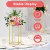 A gold rectangular flower stand with a floral arrangement on top, displayed on a table setting with plates and glasses. Produktbild-Vorschau