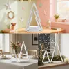 Collage of a white wooden Christmas tree decoration in different settings: on a shelf with stars and pencils, on a dining table, and on a windowsill with pine branches and a candle. Náhľad obrázku produktu