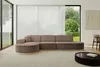 A modern living room with a large sectional sofa, large windows with sheer curtains, and a coffee table.