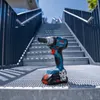 A Bosch cordless impact wrench is placed on a metal grate staircase outdoors, with a blue sky in the background. Voir les images du produit