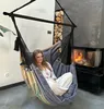 A woman relaxing in a hanging chair next to a fireplace. Produktbild-Vorschau