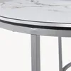 Close-up of the edge of a round table with a marble-patterned top and a silver metal frame. Voir les images du produit