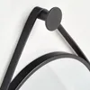 A close-up view of the black metal frame and hanging mechanism of a round mirror. Produktbild-Vorschau