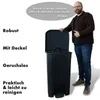 A man stands next to a black trash can, pointing to its lid. Náhled obrázku produktu