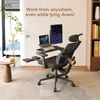 An ergonomic office chair with a laptop and monitor setup, suggesting a home office environment. Produktbild-Vorschau