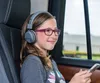 A young girl wearing headphones and glasses is sitting in a car, looking out the window and holding a phone. Produktbild-Vorschau