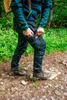 A person wearing jeans and hiking boots in a forest setting. Podgląd zdjęcia produktu