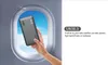 A hand holding a power bank in front of an airplane window. Produktbild-Vorschau