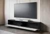 A modern TV stand with a soundbar in front of a large television, set against a neutral wall. Náhled obrázku produktu