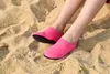 Paar hellpinke Wasserschuhe mit schwarzen Sohlen, an Füßen im Sand getragen Produktbild-Vorschau