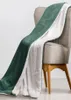 A green and white sherpa blanket draped over a chair. Produktbild-Vorschau