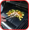 A person is using tongs to turn food on a black grill mat on a gas grill. Náhled obrázku produktu