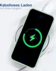 A smartphone with a green case is placed on a wireless charger, indicating charging. Produktbild-Vorschau