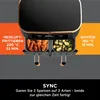 A close-up view of a dual-basket air fryer with food in each basket, accompanied by text describing cooking features. Produktbild-Vorschau