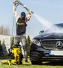 A man is pressure washing a black Mercedes-Benz car with a yellow pressure washer on a sunny day. Produktbild-Vorschau