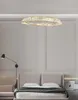 A modern bedroom with a bed, nightstand, and a large circular chandelier. Produktbild-Vorschau