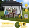 A family is enjoying a meal under a black pop-up gazebo in a garden setting. Anteprima dell’immagine prodotto