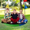 Three young boys are sitting on a large, round swing in a grassy outdoor area. Náhled obrázku produktu
