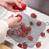 Hands washing tomatoes in a sink with a silicone drain cover. Produktbild-Vorschau