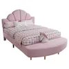 A pink upholstered bed with a scalloped headboard and a curved bench at the foot of the bed, decorated with a unicorn pillow. Produktbild-Vorschau