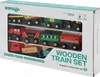 The image shows the retail packaging of a wooden train set. The front of the box is visible, displaying the product inside through a clear plastic window. The product itself consists of various colorful wooden train cars and a locomotive. Produktbild-Vorschau