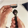 Hands holding a razor head and handle, preparing to attach them. Produktbild-Vorschau