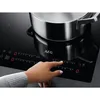 A hand is shown adjusting the controls on a black glass ceramic hob, with a pot on one of the cooking zones. Anteprima dell’immagine prodotto