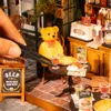 A miniature bistro scene with a teddy bear customer. Voir les images du produit