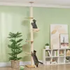 Two cats interacting with a tall, multi-level cat tree in a living room setting. Produktbild-Vorschau