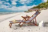 A beach scene with a lounge chair, small table, and beach bag. Produktbild-Vorschau
