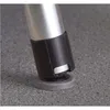 Close-up of the bottom of a silver metallic leg with a black plastic protector and a gray rubber foot, resting on a speckled gray surface. Náhľad obrázku produktu