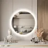 A vanity table with makeup and decor in front of a round mirror reflecting a bedroom. Produktbild-Vorschau
