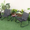A patio set with two rocking chairs and a small table on a green lawn, with plants in the background. Podgląd zdjęcia produktu