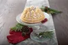 A bundt cake shaped like a pine forest, dusted with powdered sugar, is displayed on a cake stand. It is decorated with pine sprigs, pinecones, and berries, set on a table runner. Anteprima dell’immagine prodotto