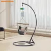 A hanging chair stand with a hammock and decorative items suspended from it, set against a window with sheer curtains. Produktbild-Vorschau