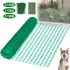 A roll of green plastic netting is shown, along with a bundle of green stakes and a sample of the netting. In the background, a section of the netting is installed as a fence. A dog is also visible in the lower right corner. Produktbild-Vorschau