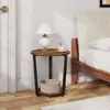 A round side table with a lamp and a cup of tea next to a bed. Produktbild-Vorschau
