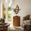 A living room scene with a wooden decorative column displaying a rope sculpture, near a window with a garden view. Voir les images du produit