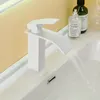 A white waterfall faucet in a bathroom sink with water flowing. Náhľad obrázku produktu