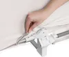 A hand is shown zipping up a beige fabric cover onto a white and gray plastic mechanism. Voir les images du produit