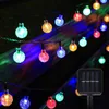 A string of colorful solar-powered LED lights is displayed outdoors at night, with a solar panel visible at the bottom right. Produktbild-Vorschau
