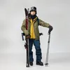 A person dressed in ski gear holding skis and poles. Náhled obrázku produktu
