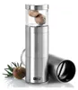 A stainless steel nutmeg grater with whole nutmegs inside and a sprig of rosemary next to it. Produktbild-Vorschau