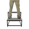 A person's legs and feet are shown standing on a two-step stool. Náhled obrázku produktu