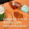 A whiskey bottle, a glass with a green drink, and wooden blocks with text are arranged on an orange surface. Produktbild-Vorschau