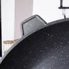 A close-up view of the handle and rim of a black frying pan with a speckled pattern. Anteprima dell’immagine prodotto