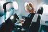 A woman wearing headphones is using a laptop and phone on an airplane. Voir les images du produit