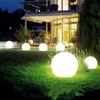 A garden at night with several illuminated spherical lights on the lawn in front of a modern house. Anteprima dell’immagine prodotto