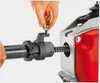 A person's hand is shown adjusting a screw on a piece of machinery. Podgląd zdjęcia produktu